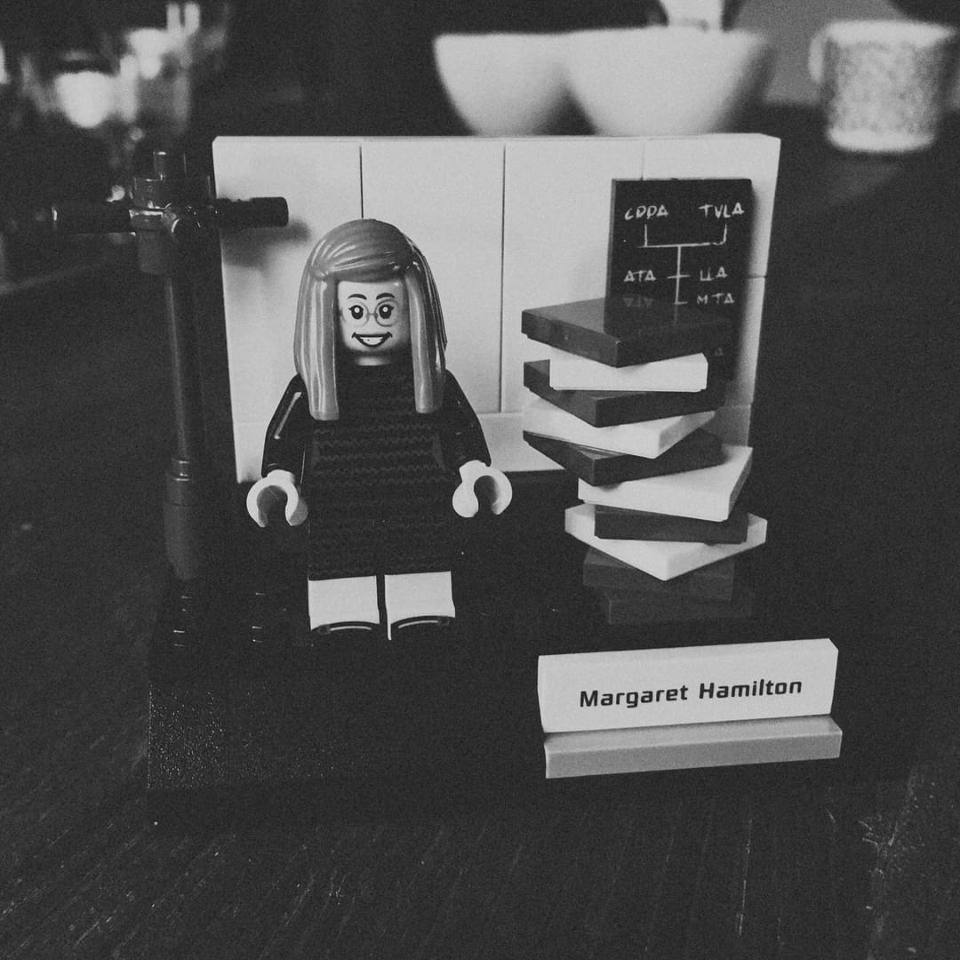 The LEGO diorama recreates a famous photo of Margaret Hamilton standing beside a stack of books containing the Apollo Guidance Computer&rsquo;s onboard flight software source code.