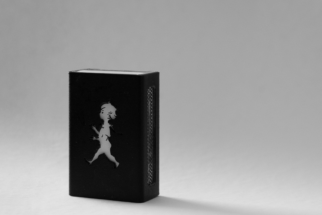 A plain, black box of matches with a worn-down striking surface. Featuring nothing else than the silhouette of a boy.