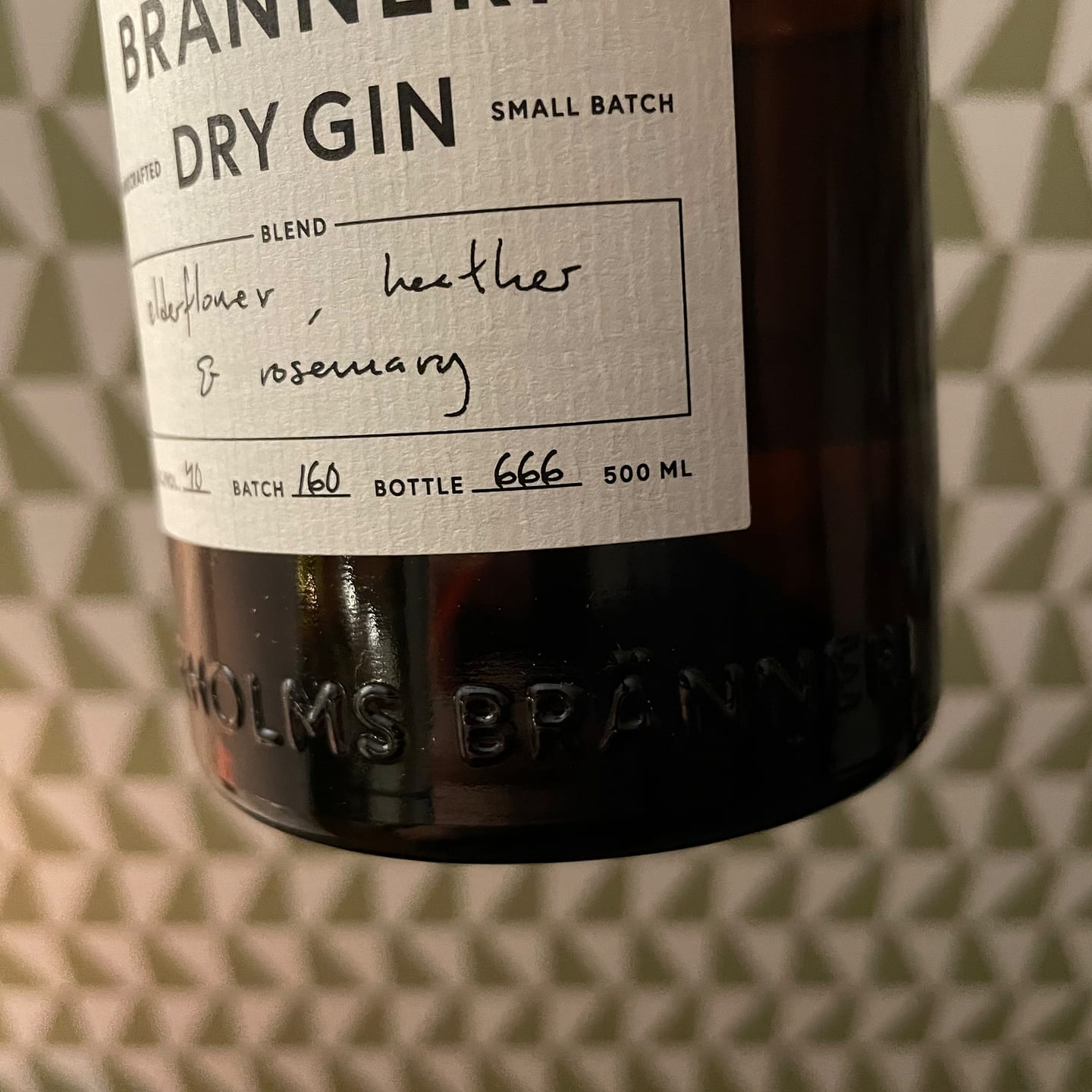 Closeup of a sturdy bottle. The label says dry gin, small batch. Bottle 666.