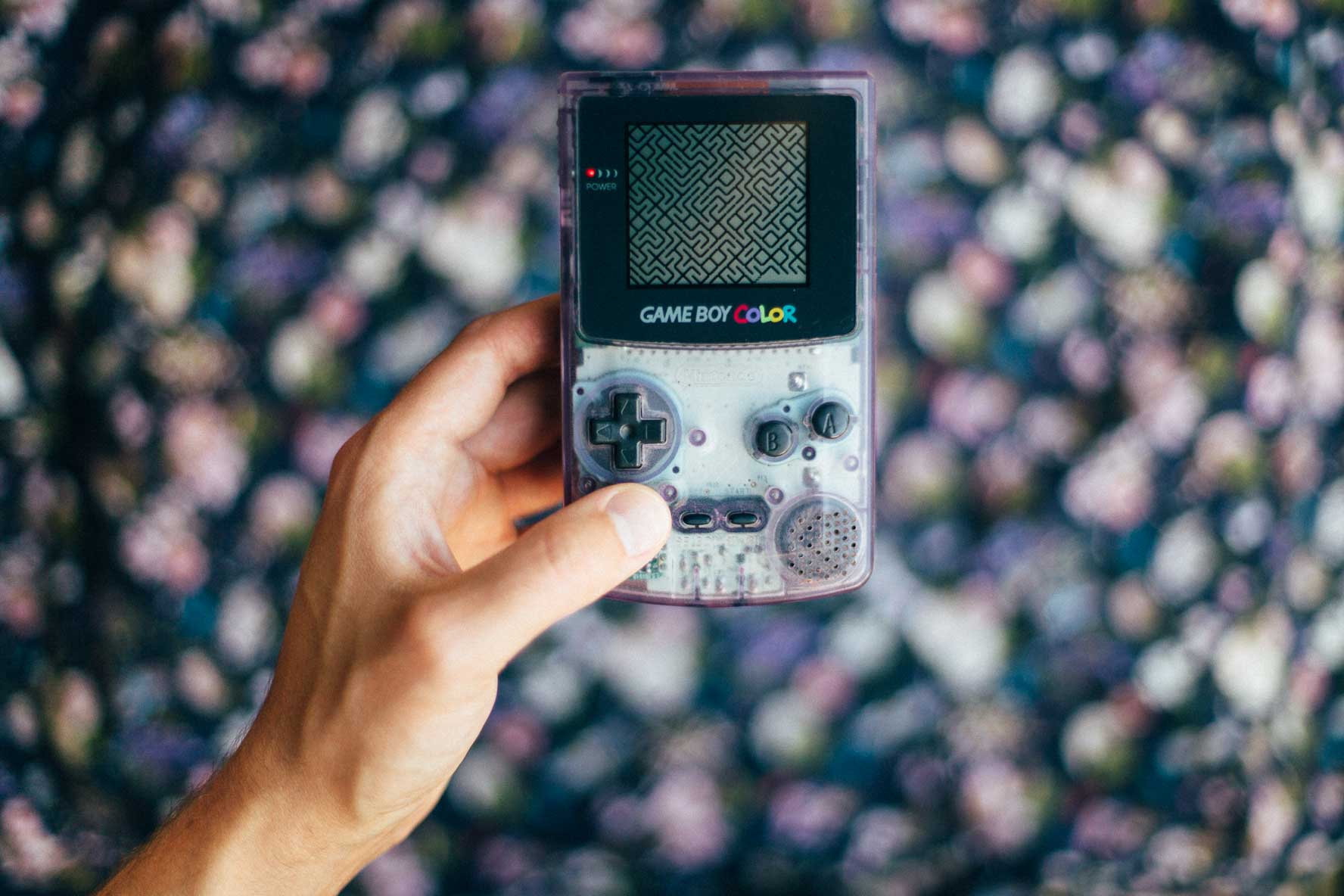 An old handheld video game in transparent, purple plastic. A black and white maze is shown on the screen, and right below it says Game Boy Color.