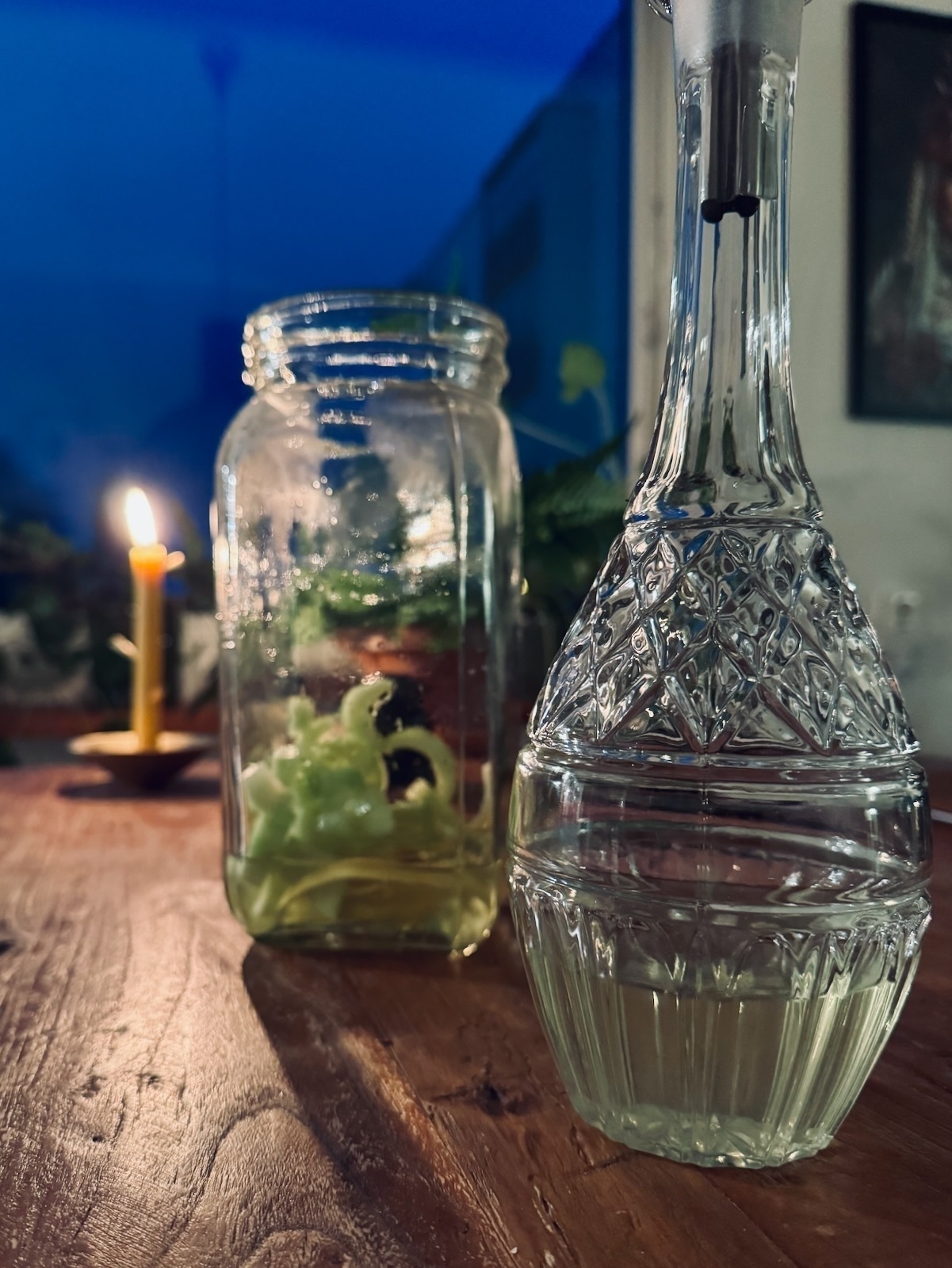 On the same table, an elegant crystal decanter and a glass jar brim with a mix of cucumber and lemon zest.