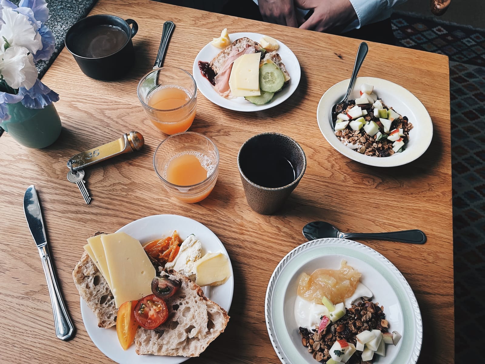 A bountiful breakfast table with coffee, apple juice, freshly baked bread, plenty of toppings, and homemade muesli.