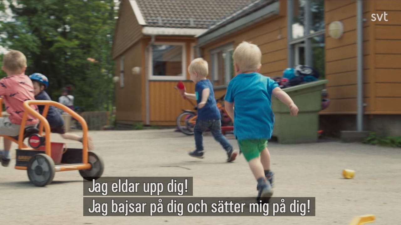 Still from a documentary. Two kids at foot screaming insults and chasing a slightly older kid on a bike. The caption, in Swedish, says: Jag eldar upp dig! Jag bajsar på dig och sätter mig på dig!