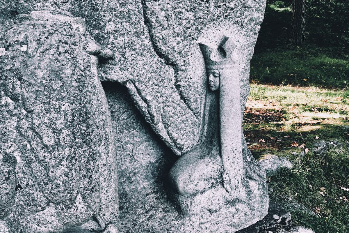 A close-up of the John Bauer monument reveals an impressive granite masterpiece. Princess Tuvstarr gracefully sits on her knees, facing a troll.