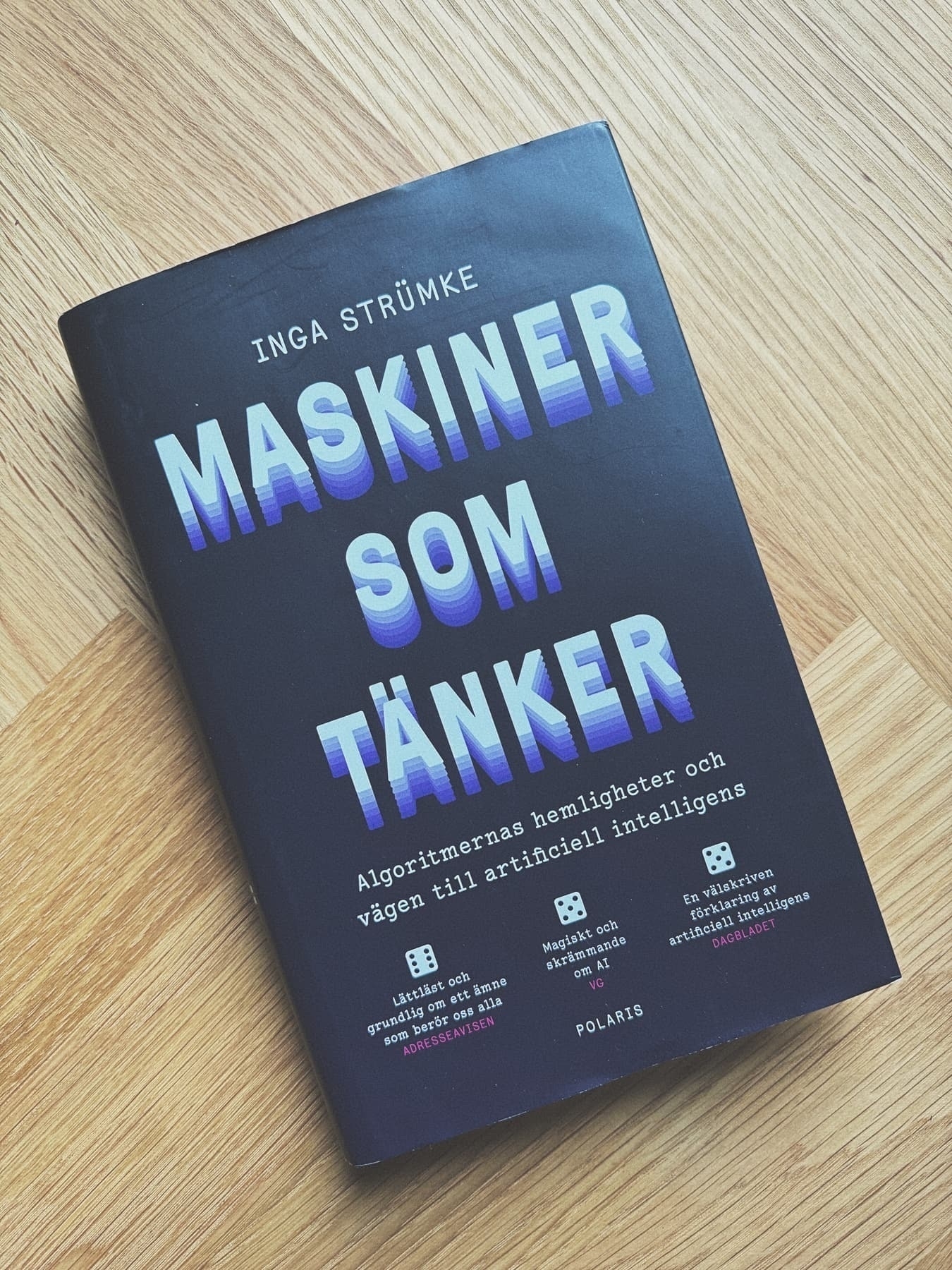 A book with the title Maskiner som tänker by Inga Strümke resting on a wooden surface.